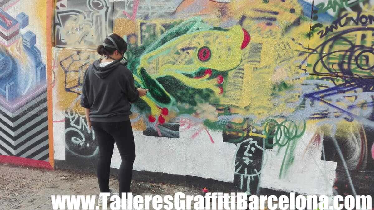 Participante pintando una rana verde con ojo rojo con spray en un curso de graffiti en Barcelona
