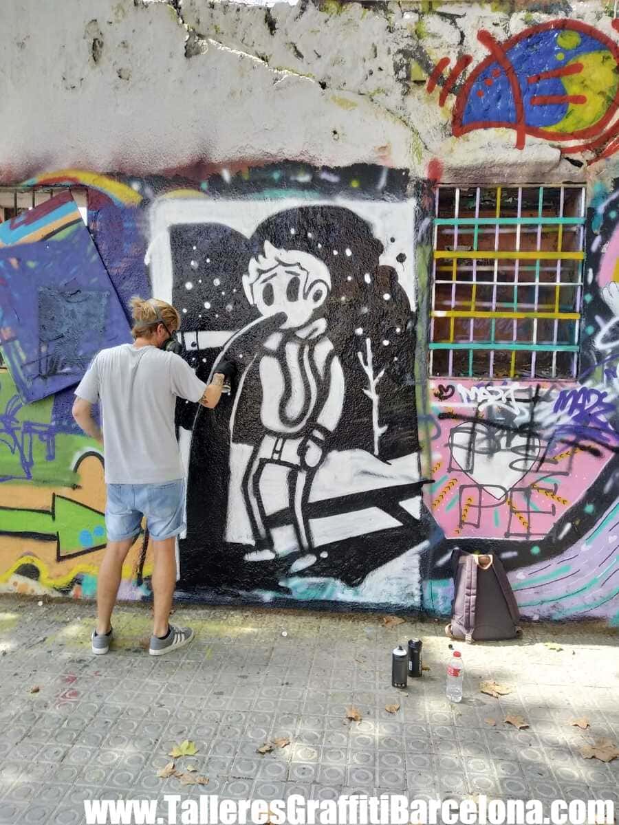 Participante pintando un personaje de cómic en blanco y negro sobre un muro en un curso de graffiti en Barcelona