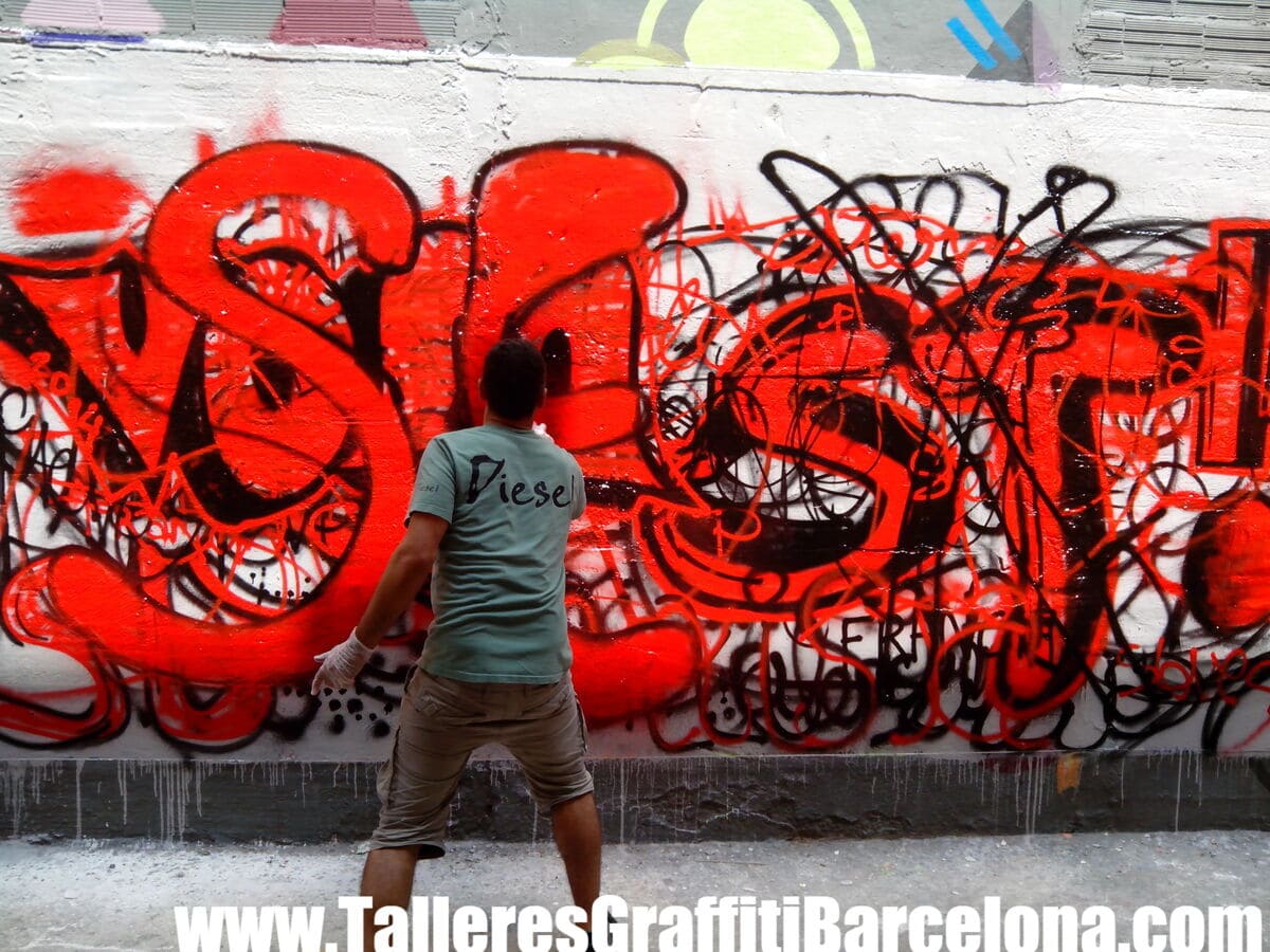 Participante pintando letras rojas con contorno negro con spray
