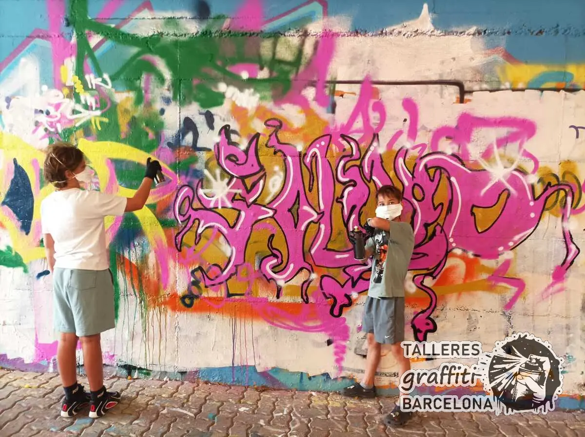 Adolescentes con mascarilla pintando letras de graffiti en spray en Barcelona