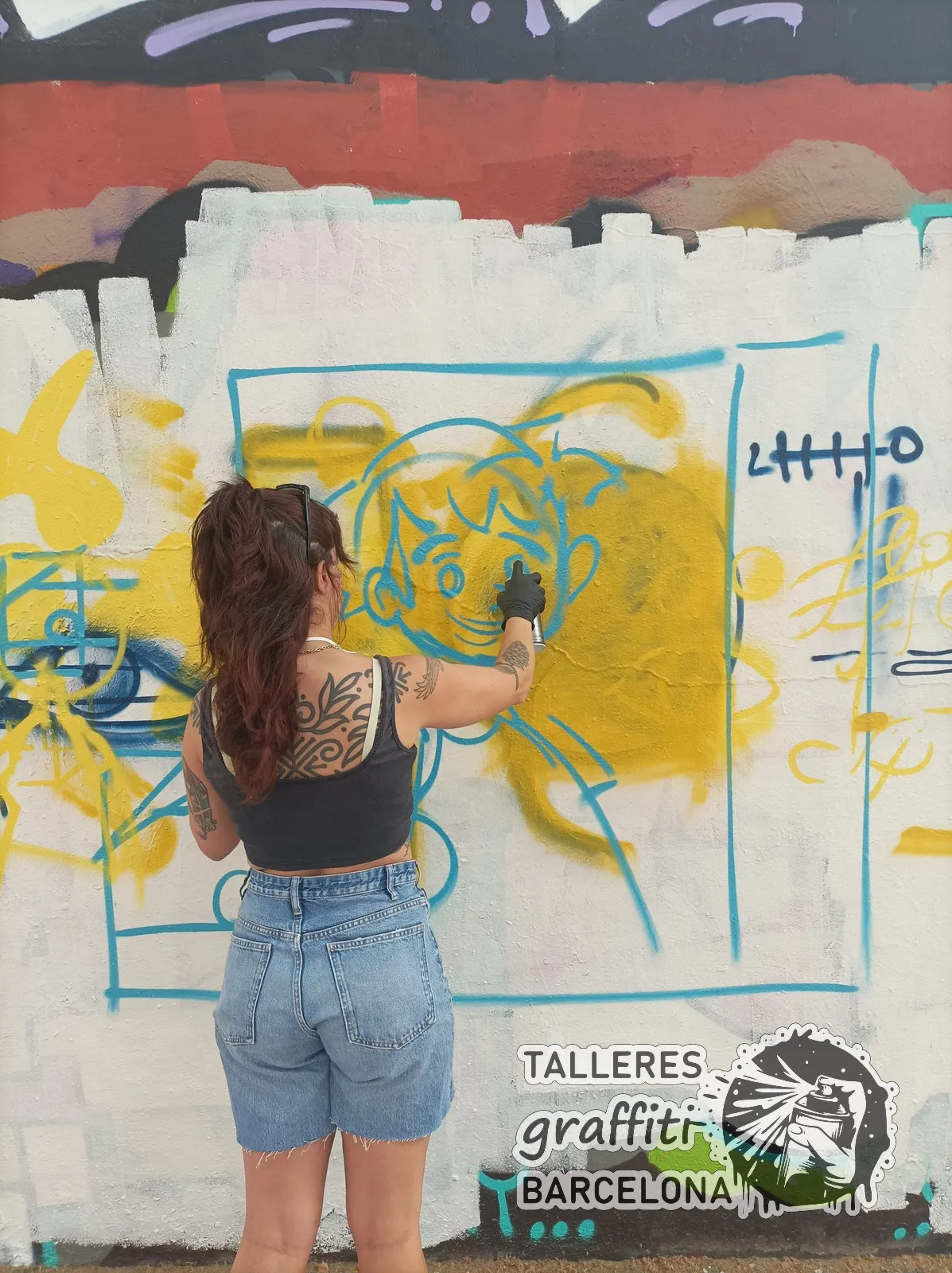 Participante pintando un personaje con spray en un curso de graffiti en Barcelona