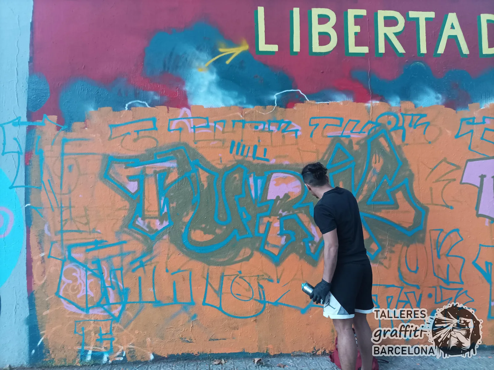 Alumno joven pintando su propio estilo de graffiti en Barcelona